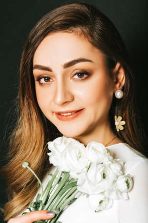 Studio close up portrait of beautiful young woman with long shiny hair, professional makeup, wearing...