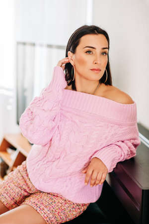 Fashion portrait of beautiful stylish woman with black hair wearing soft pink pullover and tweed shortsの写真素材