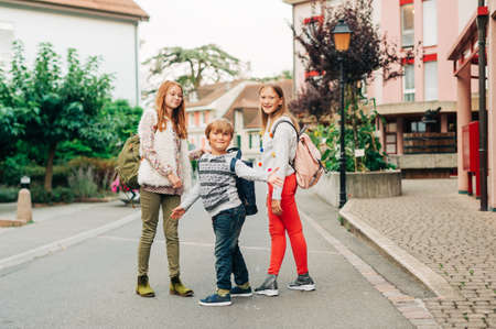 Group of 3 funny kids with backpacks, 2 schoolgirls and one preschooler, back to school conceptの写真素材