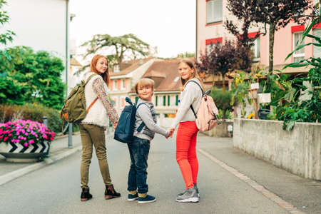 Group of 3 funny kids with backpacks, 2 schoolgirls and one preschooler, back to school conceptの写真素材