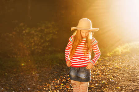 Outdoor portrait of pretty girl wearing big hat, pink stripe pullover and denim skirtの写真素材