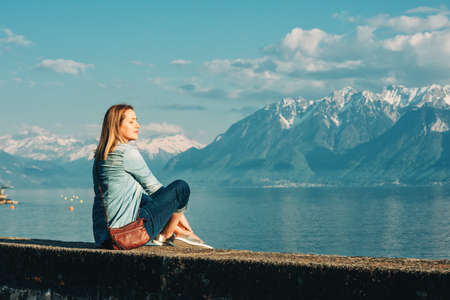 Outdoor portrait of happy young woman relaxing by the lake on a nice sunny day, peacful and harmonious moodの写真素材