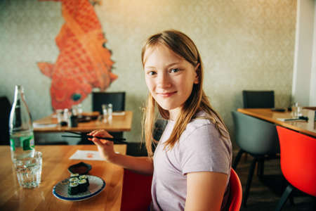 Cute kid girl eating sushi in asian restaurantの写真素材