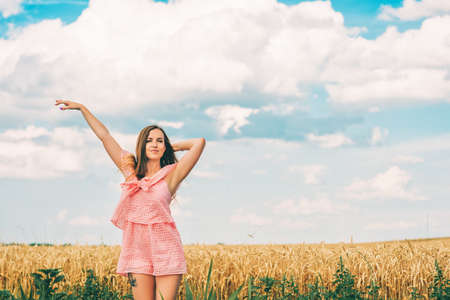 Summer portrait of happy young woman posing in wheat field