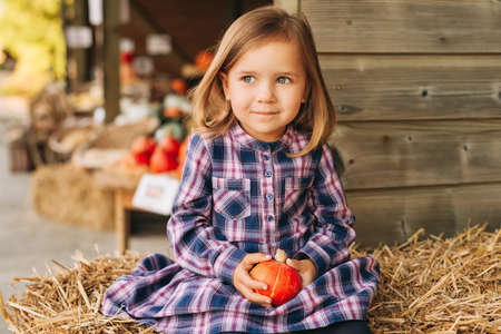 Adorable little toddler girl choosing halloween pumpkin on farm marketの写真素材