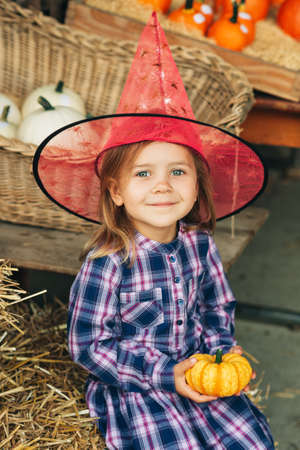 Adorable little toddler girl choosing halloween pumpkin on farm marketの写真素材