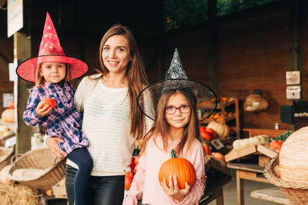 Family with kids choosing halloween pumpkin on farm marketの写真素材