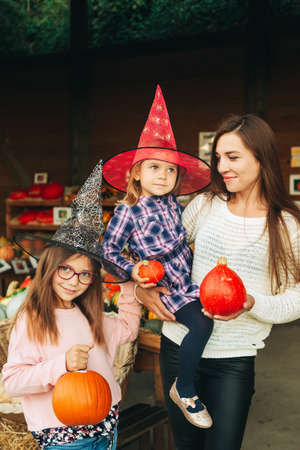 Family with kids choosing halloween pumpkin on farm marketの写真素材