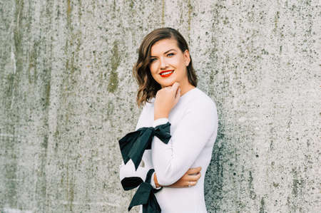 Outdoor portrait of beautiful young woman with wavy hairstyle, bright makeup red lipstickの写真素材