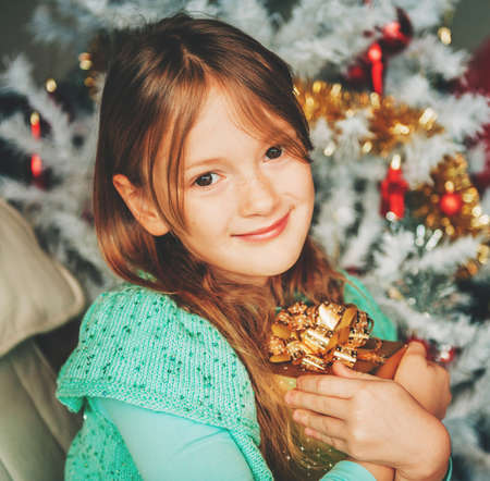 Christmas portrait of adorable little girl with white xmas tree on backgroundの写真素材