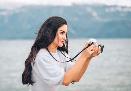 Young beautiful woman taking pictures outside with vintage film cameraの写真素材