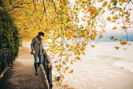 Outdoor full body fashion portrait of young beautiful fashionable woman wearing check jacket and rain bootsの写真素材