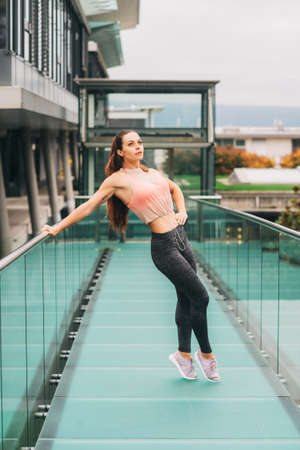 Outdoor portrait of young beautiful fit woman, wearing fashionable activewear, athlete model posing...