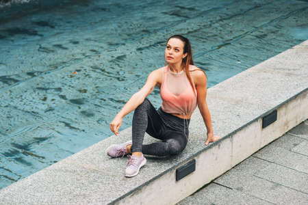 Outdoor portrait of young beautiful fit woman, wearing fashionable activewear, athlete model posing...