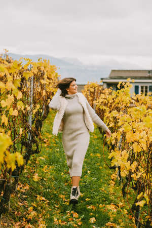 Autumn portrait of happy young woman enjoying nice day in vineyards, wearing grey knitted dressの写真素材