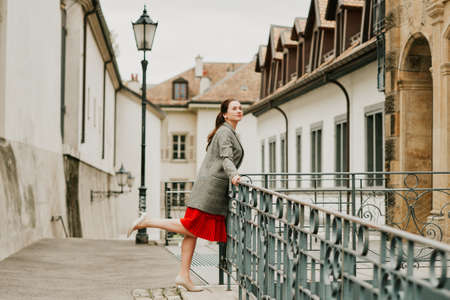 Romantic portrait of beautiful woman wearing red dress and checked coat, posing outdoorsの写真素材