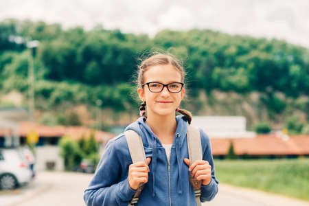 Outdoor portrait of adorable schoolgirl wearing backpackの写真素材