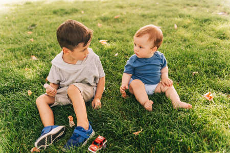 Cute toddler boy playing outside with adorable baby brother, children playing in summer parkの写真素材
