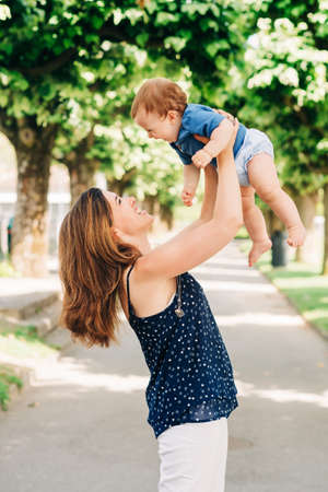 Outdoor portrait of happy mother holding adorable baby boy in armsの写真素材