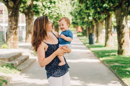 Outdoor portrait of happy mother holding adorable baby boy in armsの写真素材