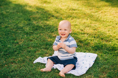 Outdoor portrait of adorable laughing baby boy playing in summer parc