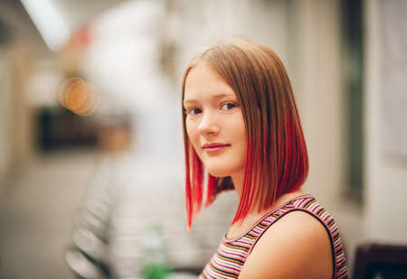 Outdoor close up portrait of pretty teenage girl with red dyed hair