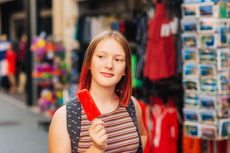Outdoor portrait of pretty teenage girl with red dyed hair posing outside with watermelon ice creamの写真素材