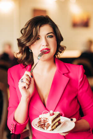 Woman eating cake Black Forest decorated with white chocolate and raspeberriesの写真素材