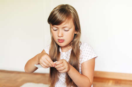 Little concentrated girl playing with paper in her room