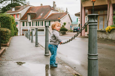 Portrait of funny toddler boy playing outside on a rainy dayの写真素材