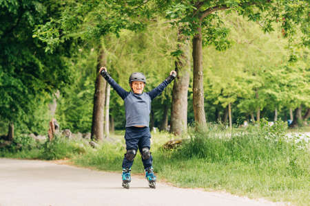 Active little boy skating in summer park, healthy lifestyle for children, holding arms up wide openの写真素材