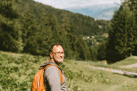 Outdoor portrait of middle age man hiking in mountains, wearing backpack, active lifestyle