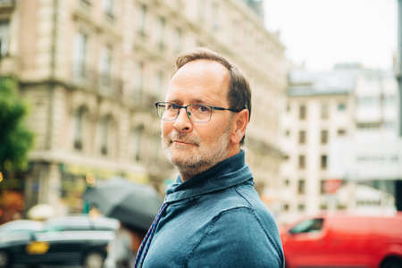 Outdoor portrait of middle age man on city street, wearing eyeglasses and blue sweatshirtの写真素材