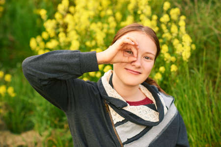 Outdoor portrait of young teen girl looking through fingers