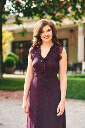 Outdoor summer portrait of beautiful young woman with brown hair, wearing long dressの写真素材