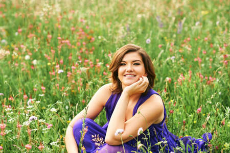 Outdoor summer portrait of beautiful woman posing between wildflowersの写真素材