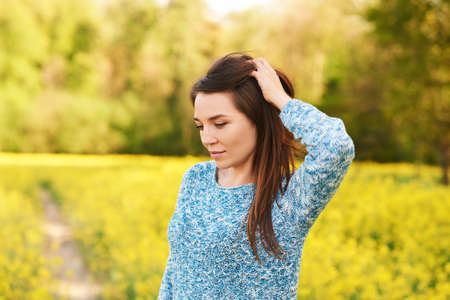 Spring portrait of happy young woman posing in colza field