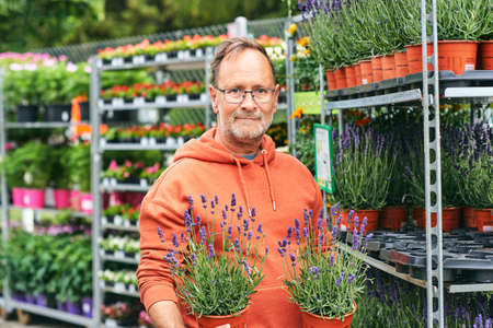 Middle age man gardener buying plants in garden centerの写真素材