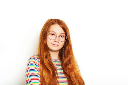 Studio portrait of pretty young teen girl with long red hair, posing on white backgroundの写真素材