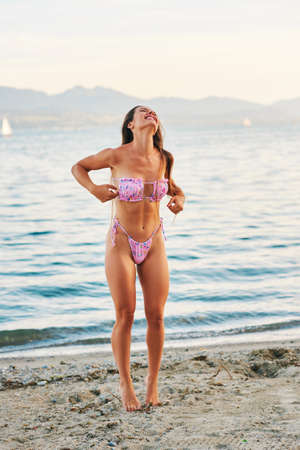 Outdoor portrait of beautiful young woman having fun by the lake, wearing pink bikiniの写真素材