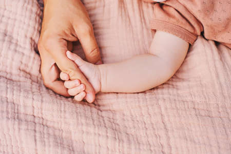Mother and baby relaxing together, child holding mothers fingerの写真素材
