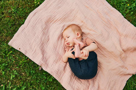 Portrait of sweet baby playing outside, child enjoying fresh air on blanket in garden or parkの写真素材
