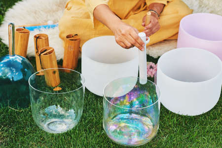 Woman playing music on crystal singing bowls, relaxing in beautiful green gardenの写真素材