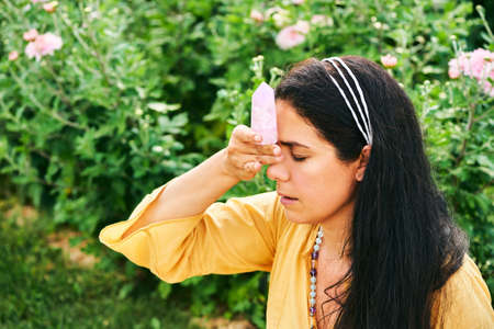 Woman healer holding natural mineral kunzite next to head