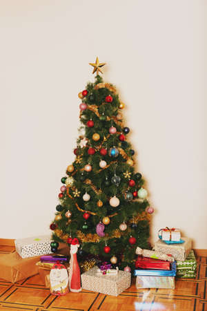 Small Christmas tree with colorful balls and gifts aroundの写真素材