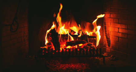 Logs burning in brick fireplace, warm and cozy winter evening