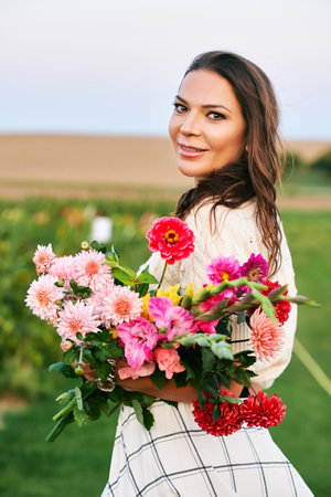 Outdoor portrait of beautiful and happy woman holding bouquet of colorful flowers, nature lifestyleの写真素材
