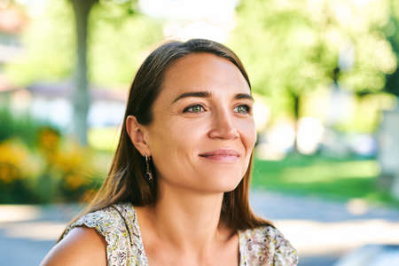Outdoor close up portrait of beautiful woman resting in summer park