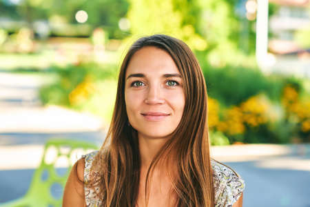 Outdoor close up portrait of beautiful woman resting in summer parkの写真素材