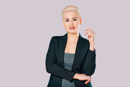 Business portrait of beautiful mature woman wearing jacket, posing on grey background, short haircutの写真素材